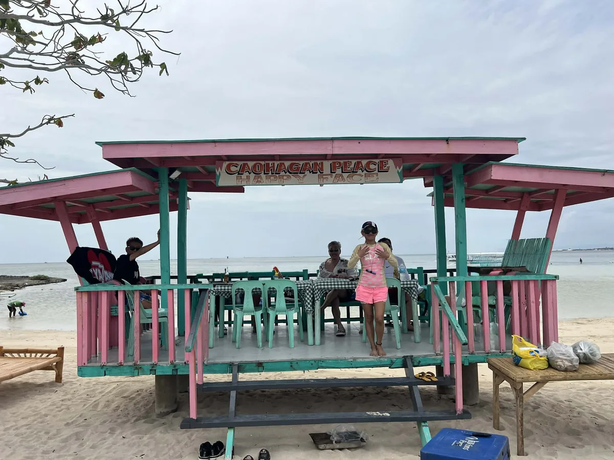 カオハガン島の浜辺に建つコテージ。CAOHAGAN PEACE HAPPY FACE と書かれた看板