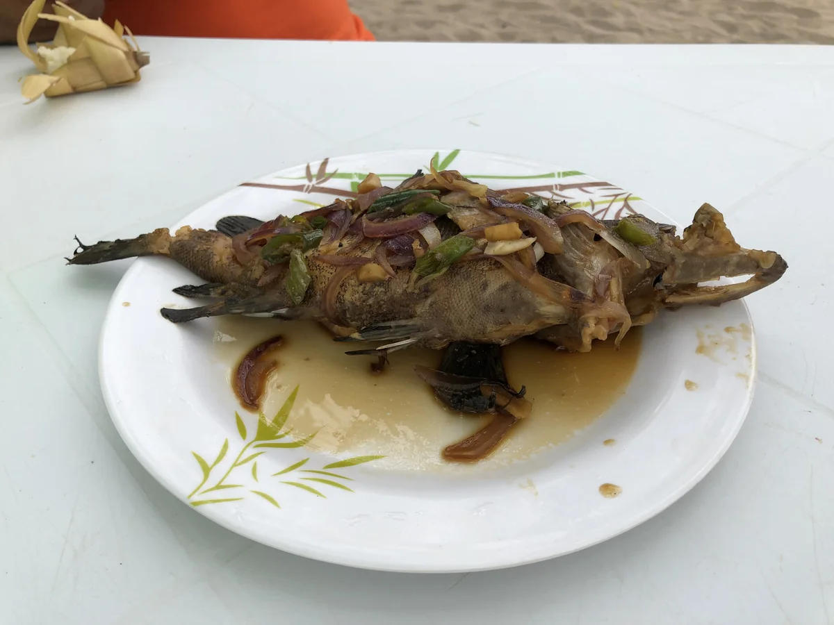 煮つけになったラプラプ。玉ねぎと青唐辛子、ニンニクが入った醤油ベースのたれがかかっている