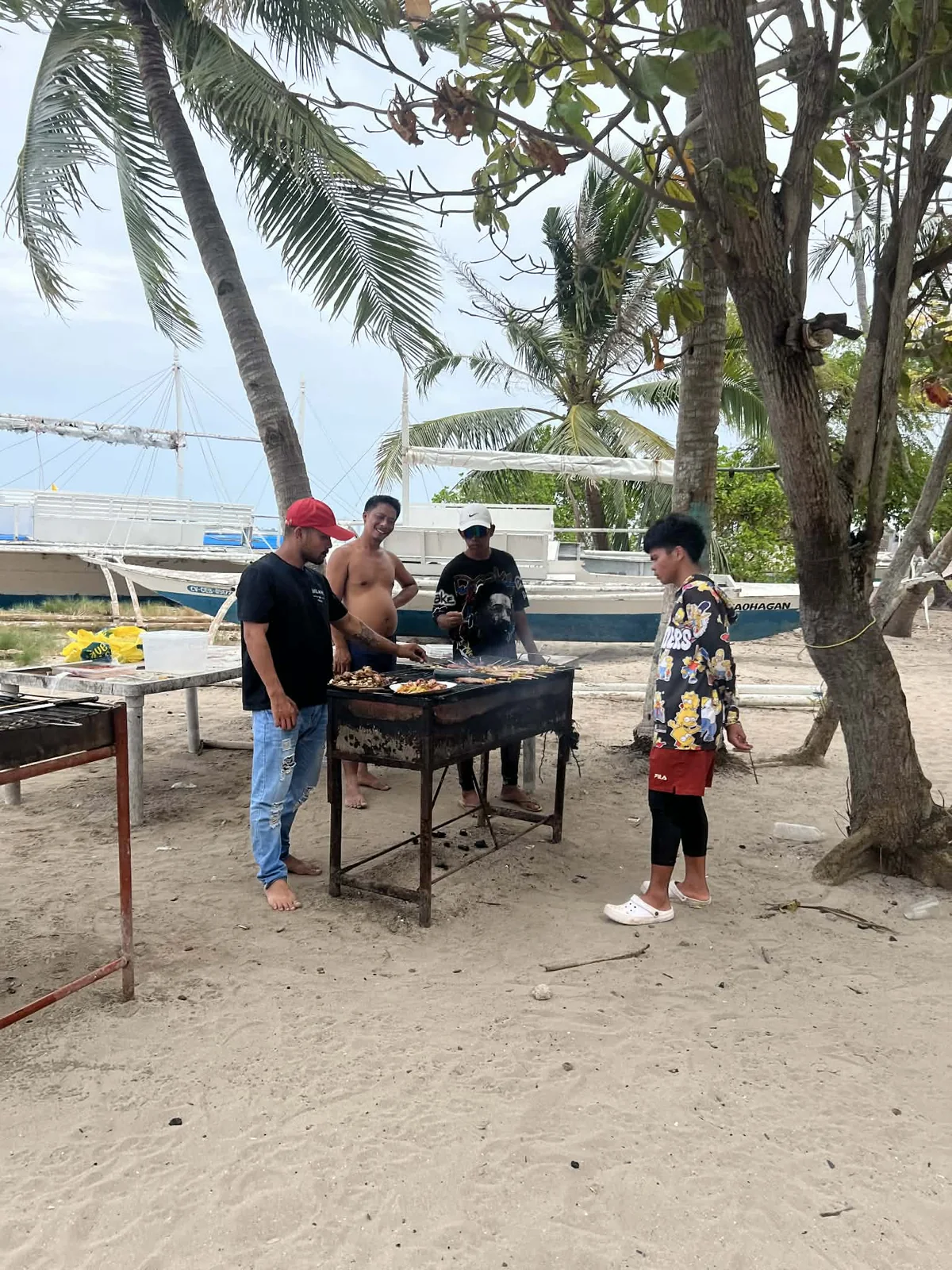 カオハガン島の浜辺でスタッフがBBQを焼いている場面
