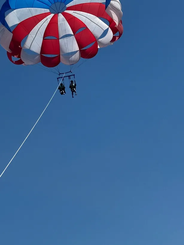 セブ島の青空に上がったパラセーリングのパラシュートと2名の参加者