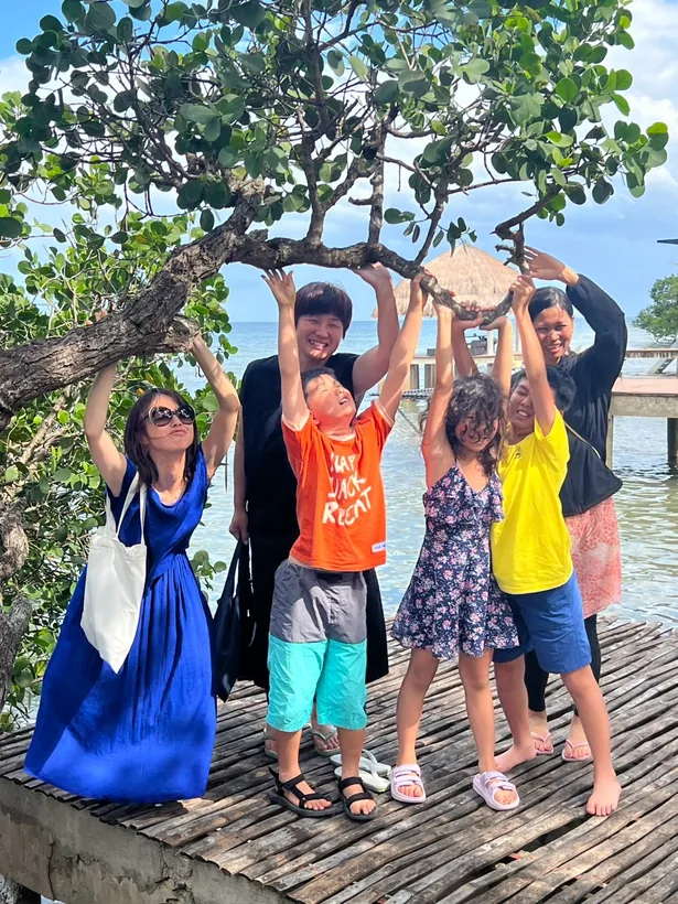 アルガオの海辺の木の下で手を伸ばして記念撮影する家族