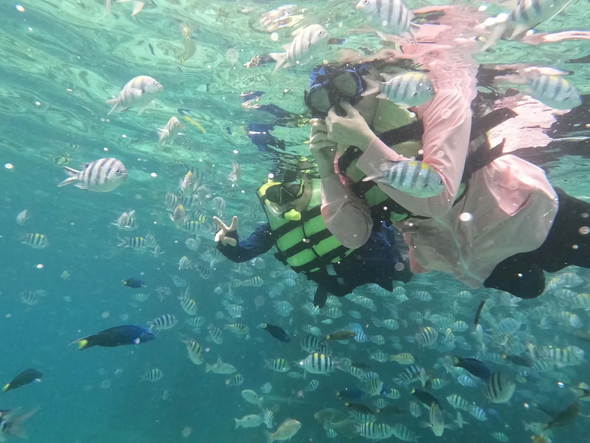 ナルスアン島の海中で熱帯魚の群れに囲まれるシュノーケラー