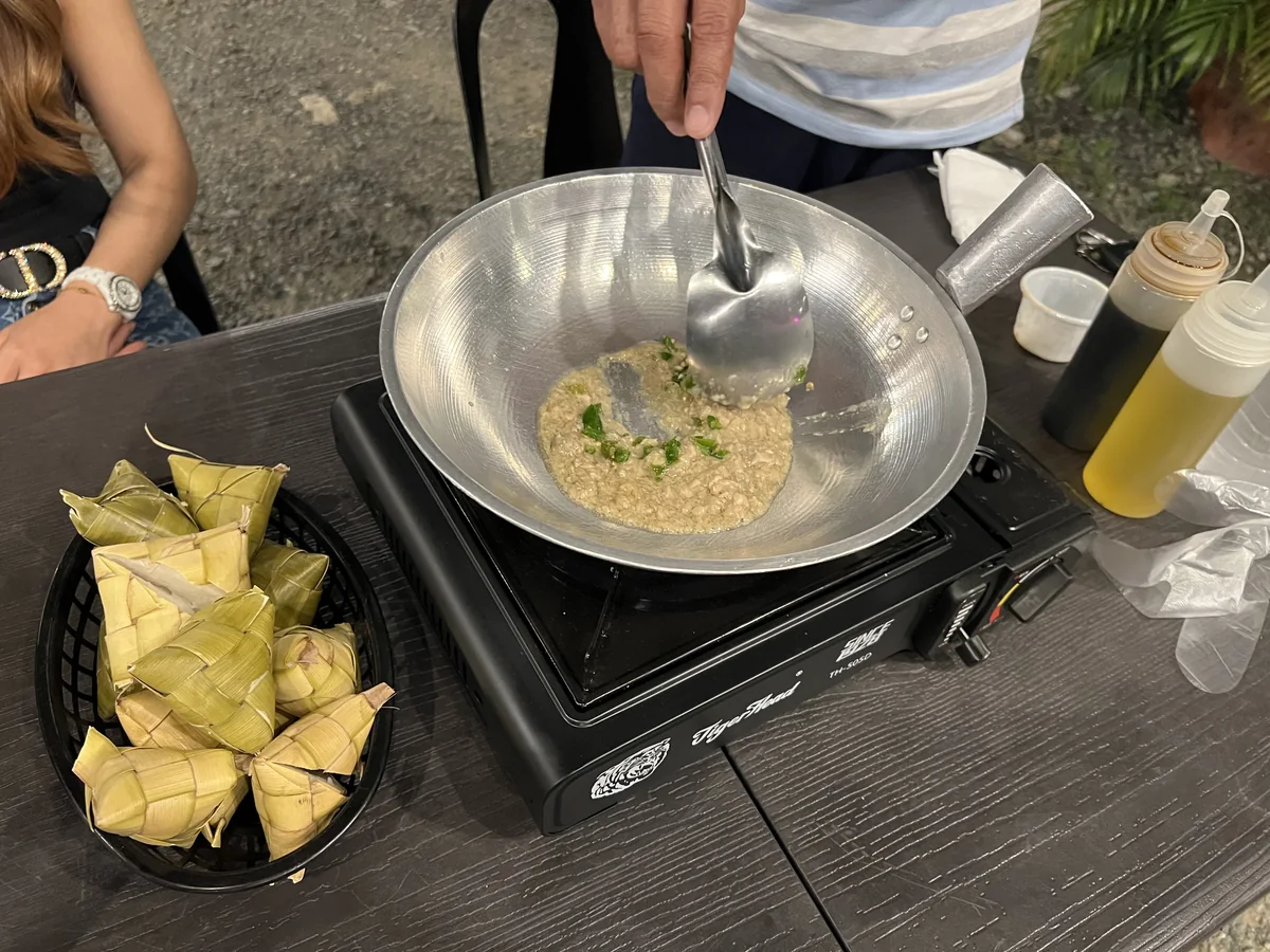 鉄鍋の中の豚の脳みそに青唐辛子と薬味を加えて混ぜているところ