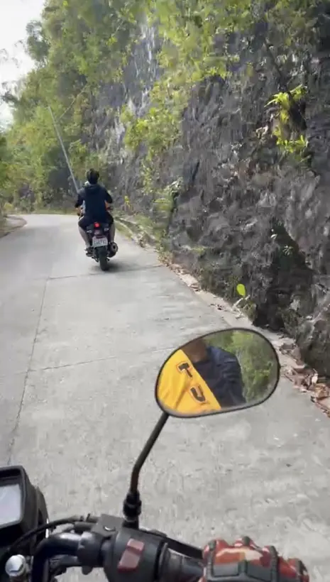 緑に囲まれた坂道をバイクで走る様子